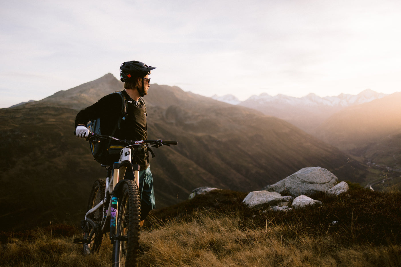 Biker mit Enduro Bike überblickt Tal im Sonnenuntergang